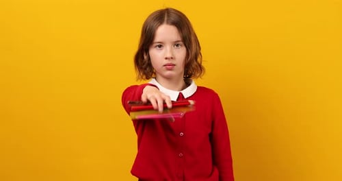 Serious Teen School Girl Holds Pencils in Her Hand in Front of Her and Throws Them