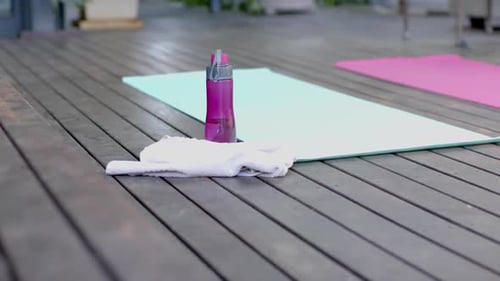 Water bottle, towel and exercise mats on sunny terrace
