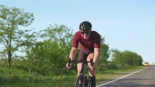 Man Riding Bicycle on Rural Road on Sunny Day