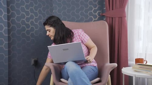 Woman Works on Laptop in Armchair at Home