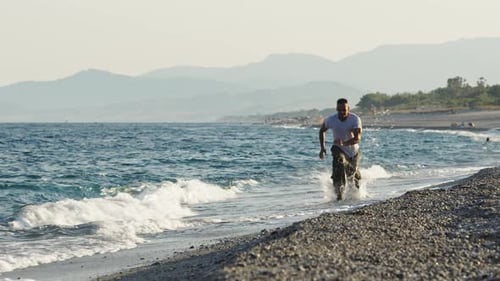 Muscular Man Doing Burpees on Beach by Ocean