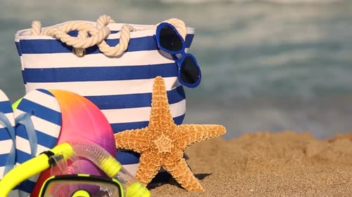 Die
Strandtasche steht auf gelbem Sand vor dem Meer. Zeitlupe