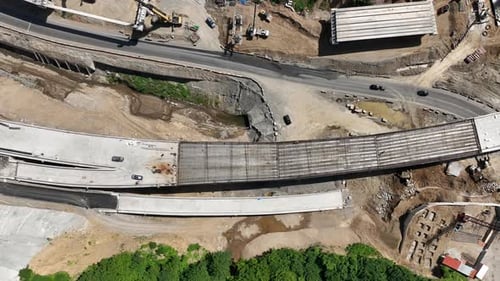 Aerial view of cranes and bridge foundation pillars on construction site of new highway road project