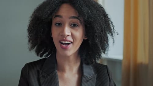 Professional Woman Speaking, Curly Hair, Brown Blazer
