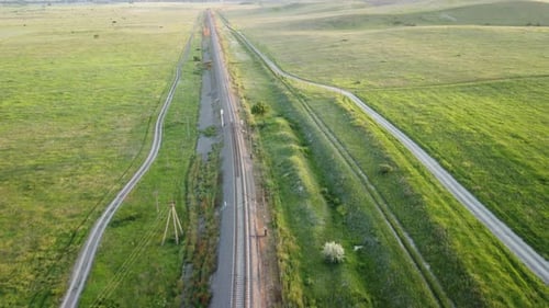 Luftaufnahme einer Eisenbahnstrecke, die durch ein üppiges grünes Weizenfeld auf dem Land führt