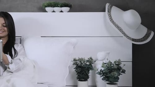 Woman Relaxes in Bed Using a Tablet Device