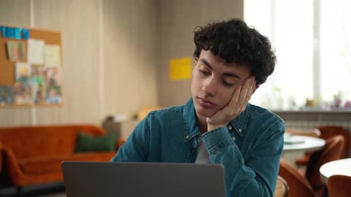 Tired Student with Laptop Resting Head on Hand