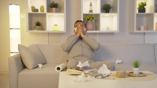 Man Blowing Nose on Couch During Daytime