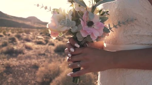 Bride Holding Wedding Bouquet in Desert at Sunset