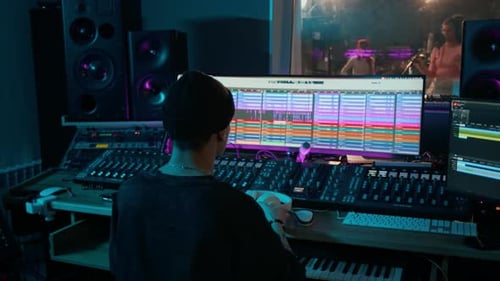 Sound Engineer Recording Music Track Using Mixing Console in Control Room