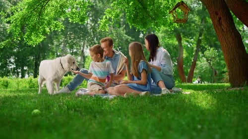 Family Relaxing on Blanket in Green Park with Dog