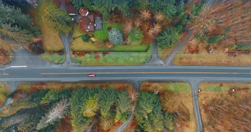 Red automobile rides by the highway in the countryside.