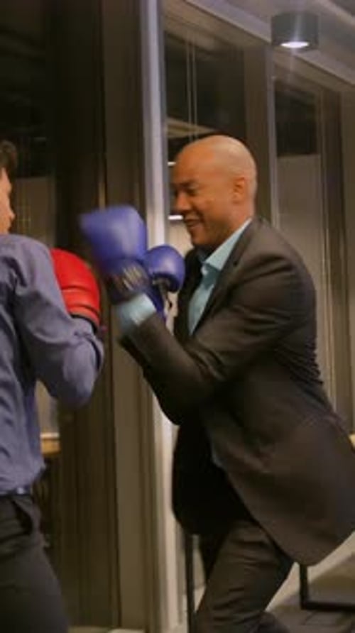 Vertical of Two Competitive Businessmen Fighting with Boxing Gloves in Corporate Office