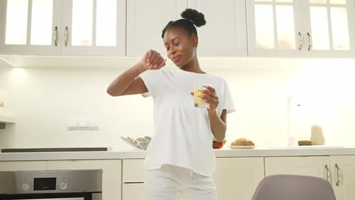 Woman Dancing with a Drink in Kitchen