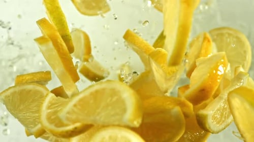 Zitronenscheiben fliegen auf hellem Hintergrund, gefilmt mit einer Hochgeschwindigkeitskamera mit 1000 Bildern pro Sekunde