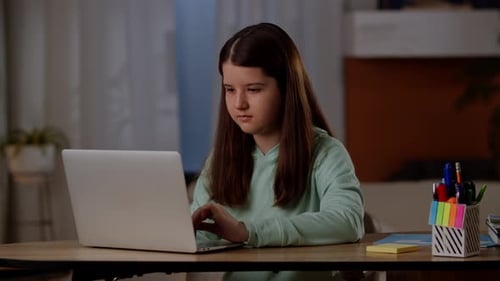 Concentrated Child Using Laptop Computer at Desk