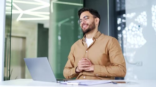 Handsome businessman finished work on laptop computer while sitting at workplace in business office.