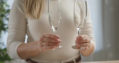 Une femme fait tinter deux coupes de champagne vides ensemble