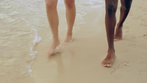 Young couple holding hands enjoying a romantic beach walk in Australia