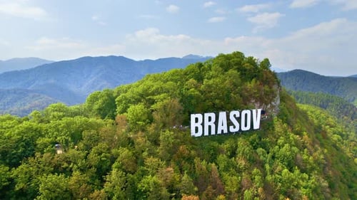 Brasov sign with tourists on the top of the hill near the city, green trees around, Romania. Old cit