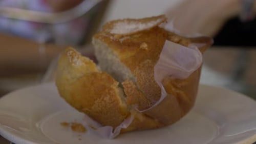 Nahaufnahme eines in einem Café aufgeschnittenen Muffins mit Menschen im Hintergrund