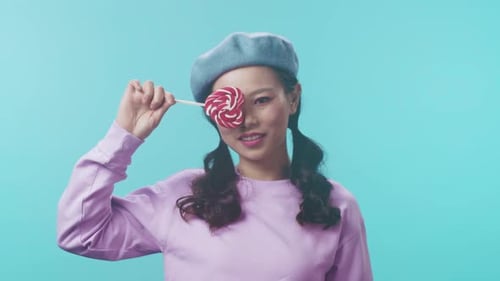 Stylish Playful Portrait Cheerful Female Model in Beret Holding Candy During Lively Studio Photo