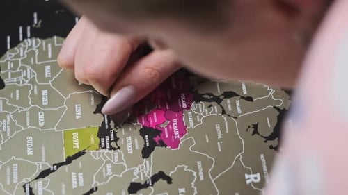 Woman Scratching Europe Countries on Surface of Scratch World Map in Slow Motion