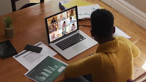Young Adult Attends Virtual Meeting at Wood Table