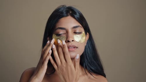 Woman Applying Gold Eye Masks for Skin Care
