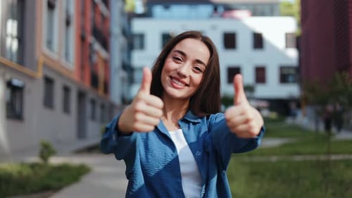 Smiling Woman Giving Two Thumbs Up Outdoors