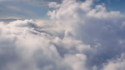 Luftflug durch flauschige weiße Wolken in einem klaren blauen Himmel