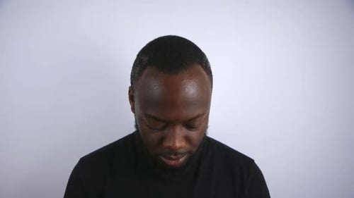 Black Male Slowly Looking Up And Smiling To Camera With White Background