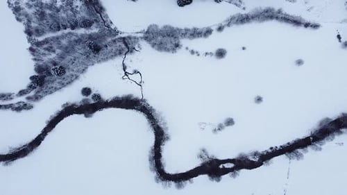 Aerial view over a mountain river covered in snow in winter