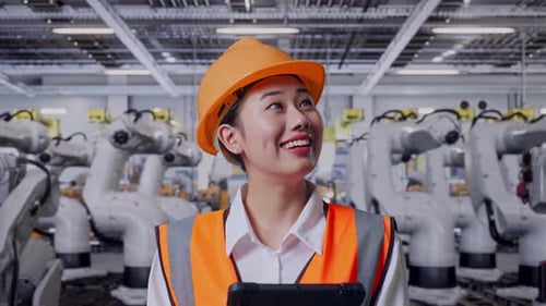 Close Up Of Asian Female Engineer Looking At The Tablet In Her Hand With Robotic Arms