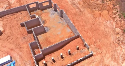 Canteiro de obras com parede de blocos de concreto para construir a base de uma casa em construção