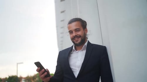 Handsome Stylish Businessman Browsing His Smartphone Near Modern Office Building
