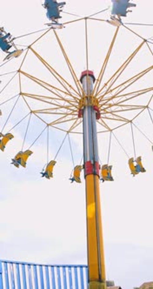 Amusement Park Swing Ride Spinning Against Bright Sky