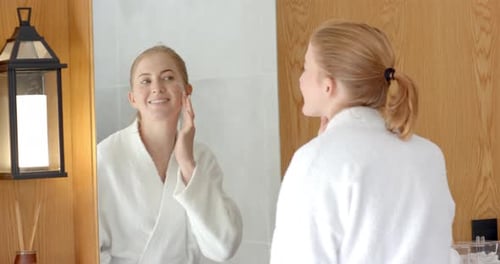 Woman Applies Lotion in Bright Bathroom Mirror