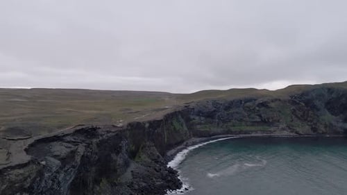 Aerial Shot Of Waterfall Flowing Into Ocean From Cliff In Iceland