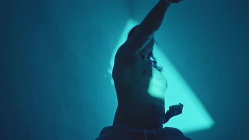 Shirtless Martial Artist Under Teal Light Controlled Punch Into Triangular Backlight Moody Studio