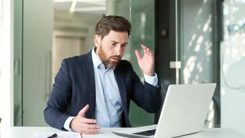 Frustrated Businessman Working on Laptop in Modern Office