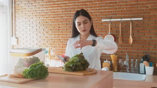 Woman Prepares Salad in Bright Kitchen