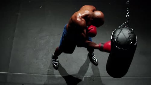 Athletic Boxer Punches Heavy Bag From Overhead Perspective