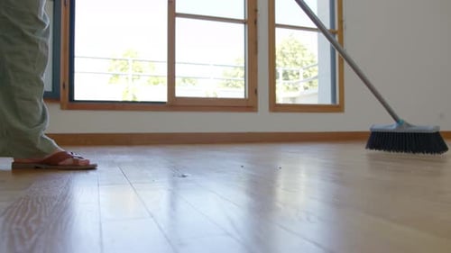 Person Sweeping Over Wooden Floor Of A House. Close-up Shot