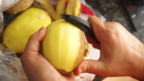 peeling potatoes close up with a potato peeler