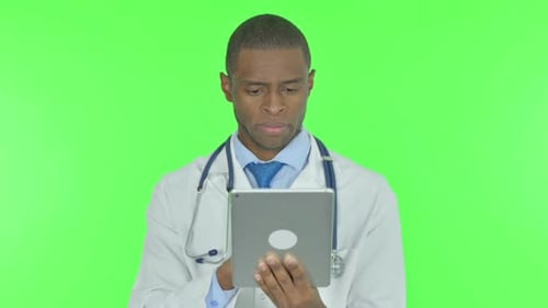 African Doctor using Digital Tablet on Green Background