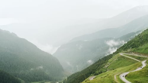 Curvy Mountain Road Through Green Forest Valley with Trees Villages and Rainy Fog