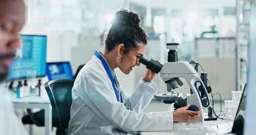 Female Scientist Using Microscope in Bright Lab