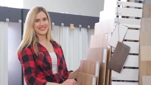 A Beautiful Girl Seller Offers Laminate to Customers in a Building Materials Store