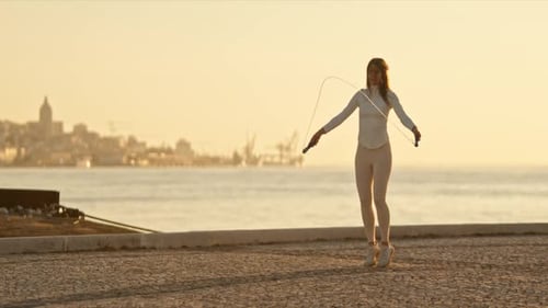 Sportswoman Jumping Rope By the Sea at Sunrise